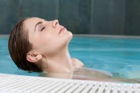 Een vrouw die in een zwembad ligt en wordt geholpen door middel van hydrotherapie