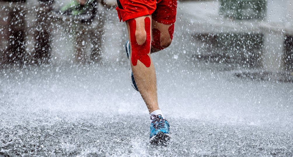 Sportfysiotherapie: jogger met tape om knie traint buiten