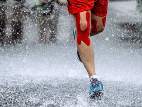 Sportfysiotherapie: jogger met tape om knie traint buiten