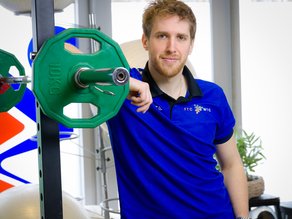 Personal trainer Floris Hakvoort leunt tegen een halter in de oefenruimte