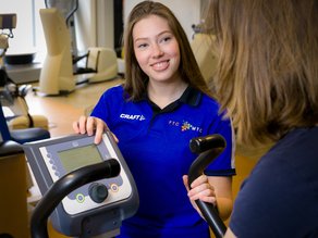 Renate Steltman ondersteunt een cliënt tijdens oefeningen op een apparaat
